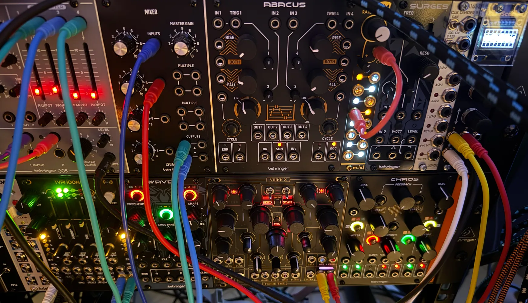 A close view of patched modular synthesiser modules with coloured cables and lit controls.